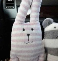 two stuffed animals sitting in the front seat of a car, one is wearing a bunny costume