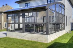 an enclosed patio in front of a house with large windows on the side of it