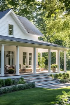 a white house with porches and steps leading up to the front door is surrounded by greenery