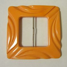 an orange plastic frame with a metal clip in the shape of a rectangle, on a white surface