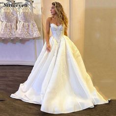 a woman in a white wedding dress standing next to a rack with dresses on it