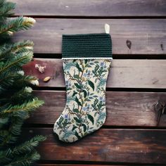 a christmas stocking hanging on a wooden wall next to a pine tree and other decorations