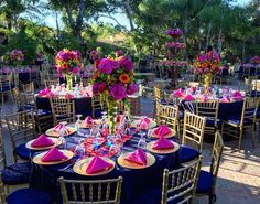 a table set up with purple and pink flowers in vases, plates and napkins