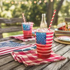 an american flag drink on a picnic table with patriotic napkins and plates in the background