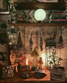 a shelf filled with assorted items and candles on top of a wooden table in front of a brick wall