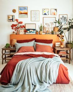 a bed with red and blue sheets in a room filled with pictures on the wall