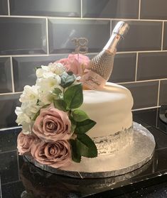 a wedding cake decorated with flowers and a champagne bottle