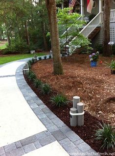 a walkway in front of a house with trees and plants on the side walk way