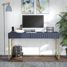 a desk with a computer and luggage on it next to a potted palm tree