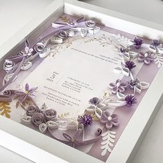 an open box with paper flowers on it and a card in the bottom right corner