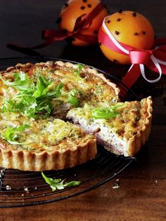 a quiche on a wire rack with an orange in the background