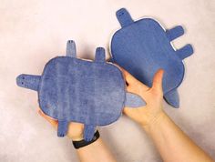 someone is holding two pillows in the shape of an animal, one blue and one brown