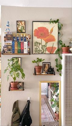 there are many plants and pictures on the wall in this room, including an orange flower