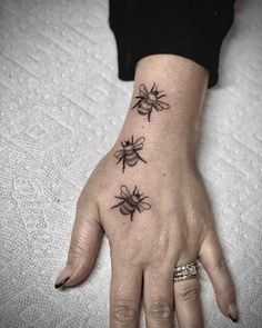 a woman's hand with three bees tattooed on the left side of her wrist