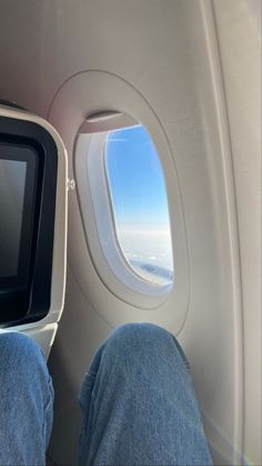 the view from inside an airplane looking out at the wing and window with someone's feet propped up