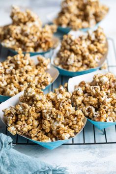 several blue bowls filled with popcorn sitting on top of a cooling rack next to a towel