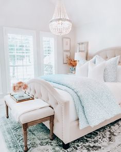 a white bed sitting in a bedroom on top of a rug next to a window