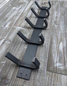 three black metal brackets sitting on top of a wooden floor