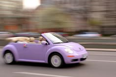 a purple car driving down the road with a stuffed animal in it's seat