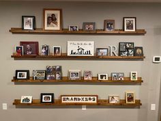 three wooden shelves filled with pictures and framed photographs on them, along with other family related items