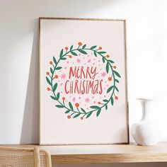 a white vase sitting on top of a wooden table next to a framed christmas card