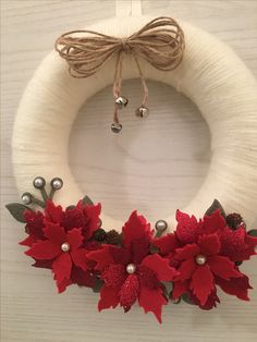 a white wreath with red poinsettis and bells