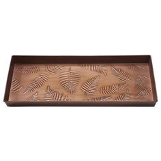 a metal tray with leaves on the front and bottom, in brown color is sitting on a white surface