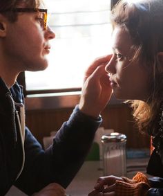 a man and woman sitting next to each other in front of a window with sunlight streaming through them