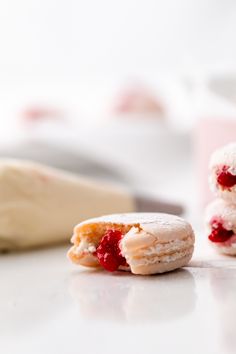 two powdered donuts with raspberry filling on the top one is half eaten