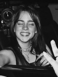 a black and white photo of a smiling woman in a car with her eyes closed