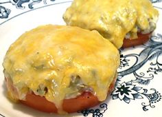 two hot dogs covered in cheese sitting on top of a plate