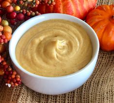 a white bowl filled with hummus next to pumpkins and gourds