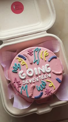 a pink cake in a plastic container with writing on it