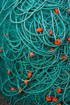 green fishing nets with orange balls on them are piled together and ready to be used