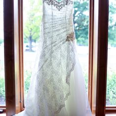 a wedding dress hanging on a window sill