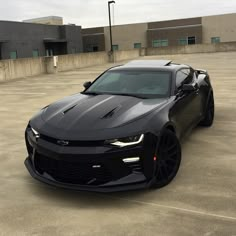 a black chevrolet camaro is parked in an empty parking lot next to a building