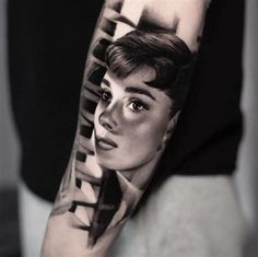 a woman's arm with a black and white portrait tattoo on the left upper arm