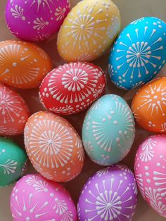 many colorful eggs with white designs on them