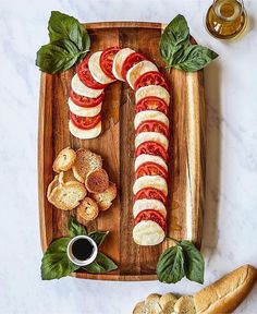 sliced tomatoes, mozzarella and basil on a wooden platter with garlic bread