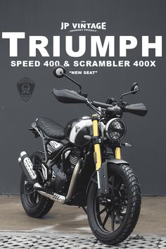 a black and white motorcycle parked in front of a wall with the words triumph on it