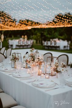 a table set up with candles and flowers for a wedding reception in the evening time