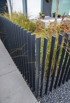 a black metal fence with grass growing between it