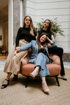 three women are sitting on an orange chair