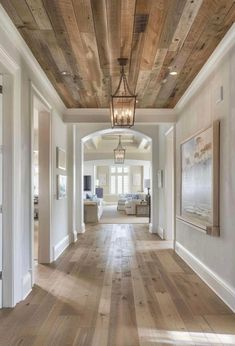 a long hallway with wood floors and white walls is lit by a hanging light that hangs from the ceiling