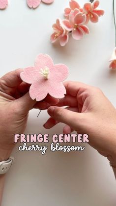 someone is making pink flowers out of felt and yarn with the words fringe center cherry blossom