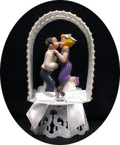 a wedding cake topper with a bride and groom kissing in an arch shaped like a heart