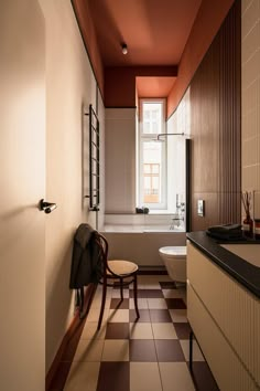 a bathroom with a checkered floor, tub and chair in the corner by the window