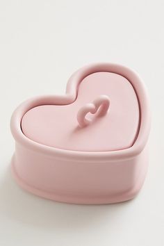 a pink heart shaped container sitting on top of a white table