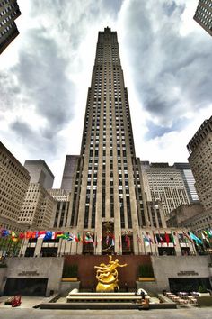 an upward view of the rockefeller building in new york city, with flags flying from it