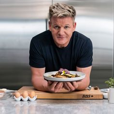 a man sitting at a kitchen counter holding a plate with food on it